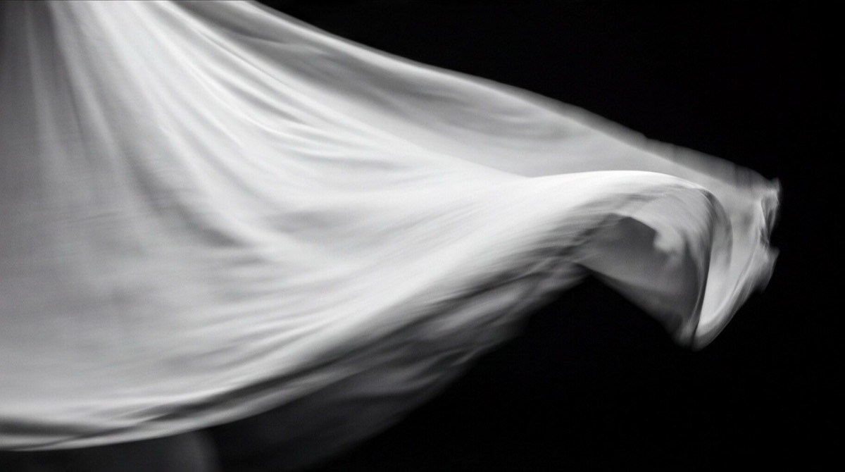 White fabric moving through darkness